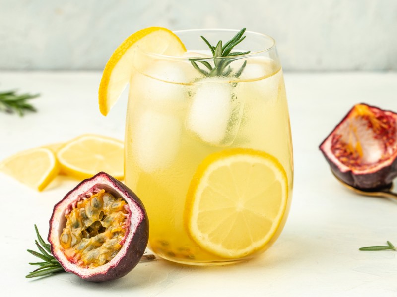 Gelber Cocktail mit passionsfrucht und Eiswürfel.