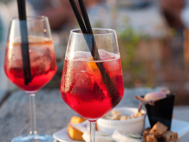 Lillet Ruby Cocktail in einem Glas auf einem Terrassentisch.