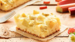 Blechkuchen mit Pudding und Rhabarber auf einem Stück Backpapier.