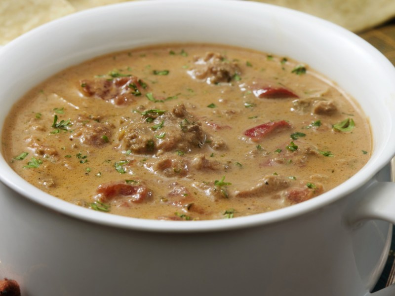 Suppe mit Tomaten, Hackfleisch und Paprika in weißer Schüssel.