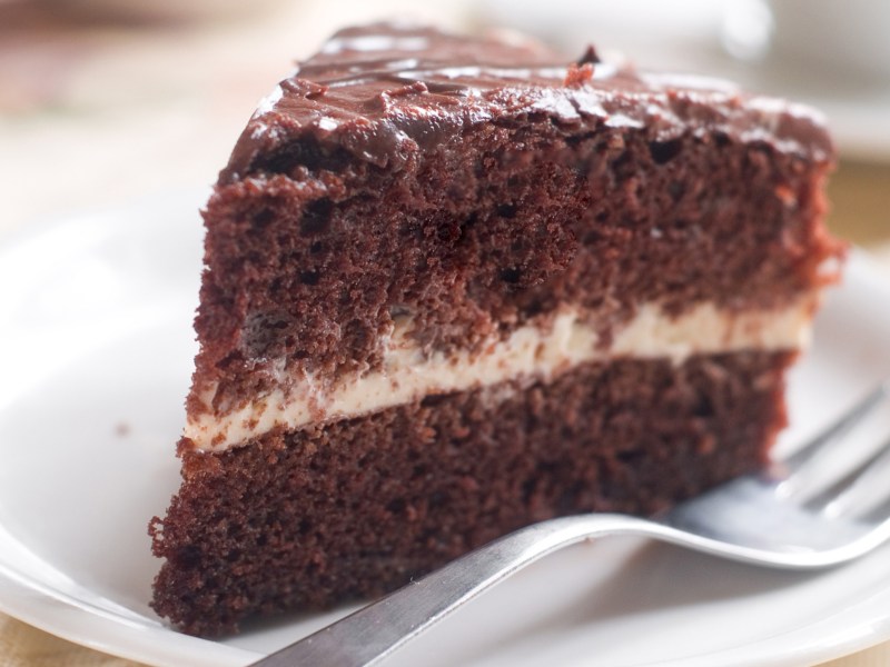 Schokotorte mit Sahne in der Mitte auf einem weißen Teller.