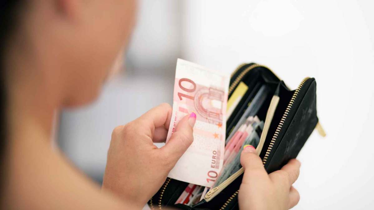 Frau legt 10-Euro-Schein in ihr Portemonnaie.