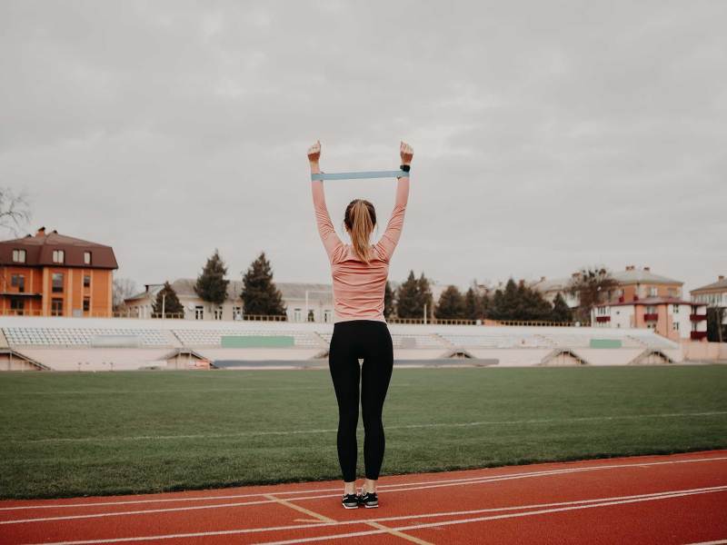 Sportliche Frau macht Übung mit Widerstandsband. Weibliche Athletin arbeitet an ihrer Fitness.