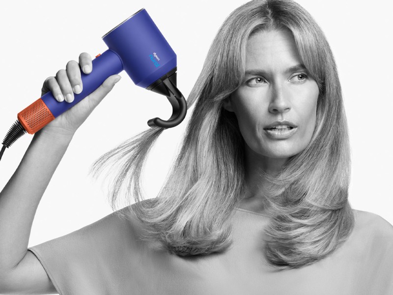 Model hält den neuen Supersonic Nural Föhn von Dyson in der Hand.