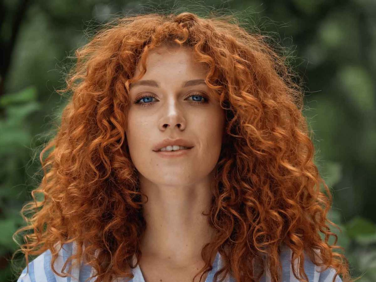 Schöne rothaarige Frau steht im Garten.