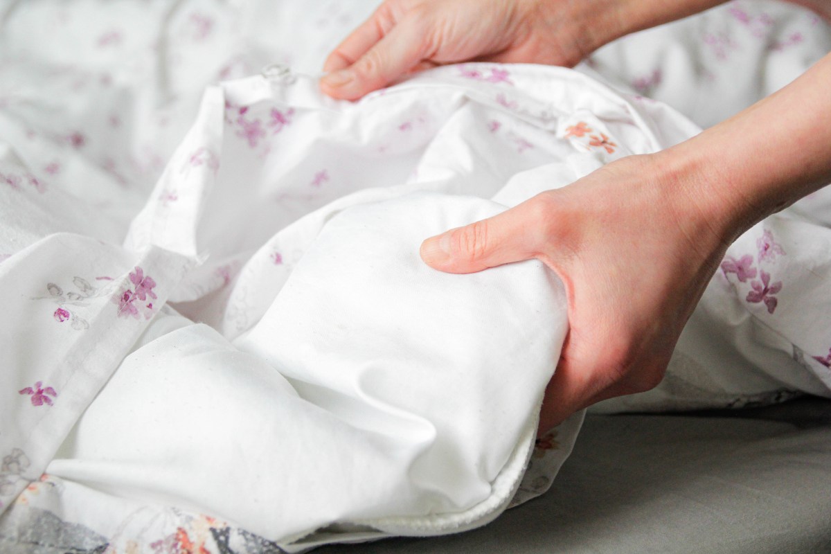 Bettwäsche wechseln: Hand öffnet bettbezug