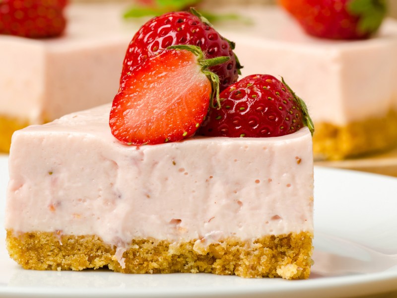 Ein Stück Erdbeer-Cheesecake auf einem weißen Teller.