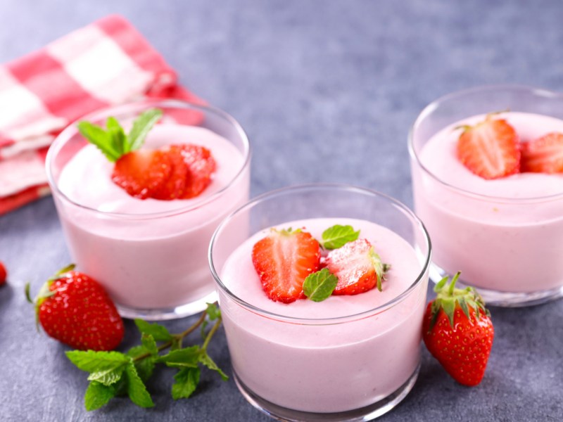 Drei Glasschalen mit Erdbeermousse und frischen Erdbeeren.