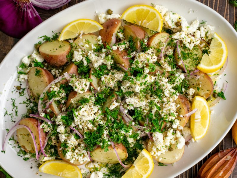 Kartoffelsalat mit Feta und Zitronen auf großem Teller.