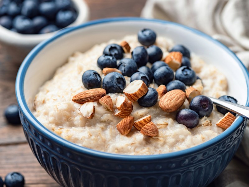 Porridge mit Blaubeeren und Mandeln in einer blauen Schüssel.