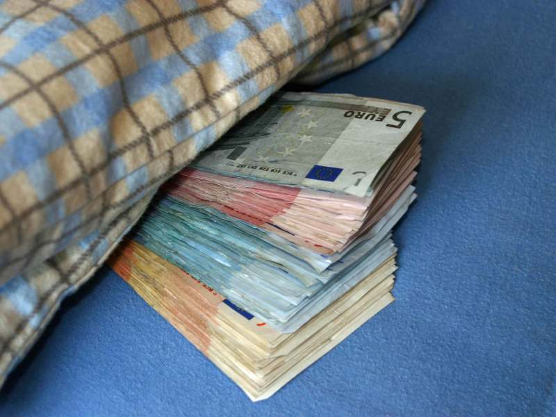 Bargeld liegt zur Hälfte unter einer Decke.
