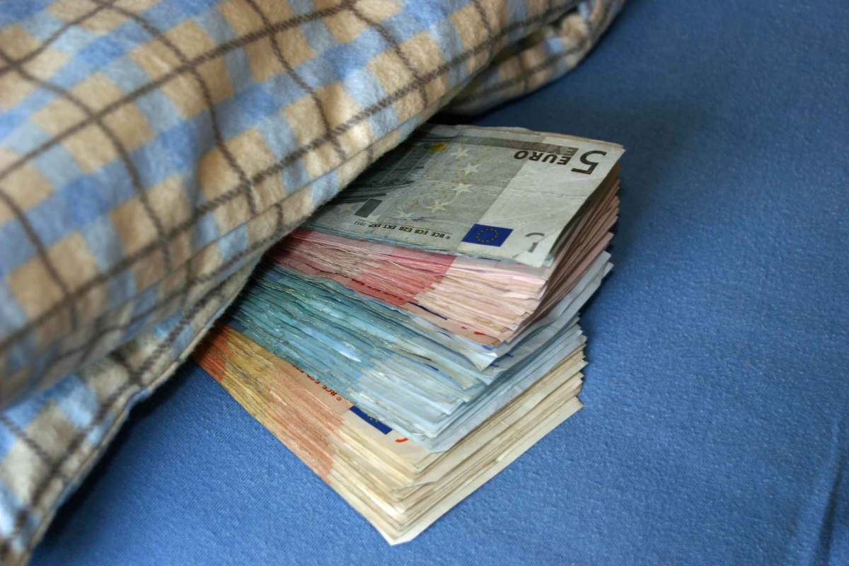 Bargeld liegt zur Hälfte unter einer Decke.