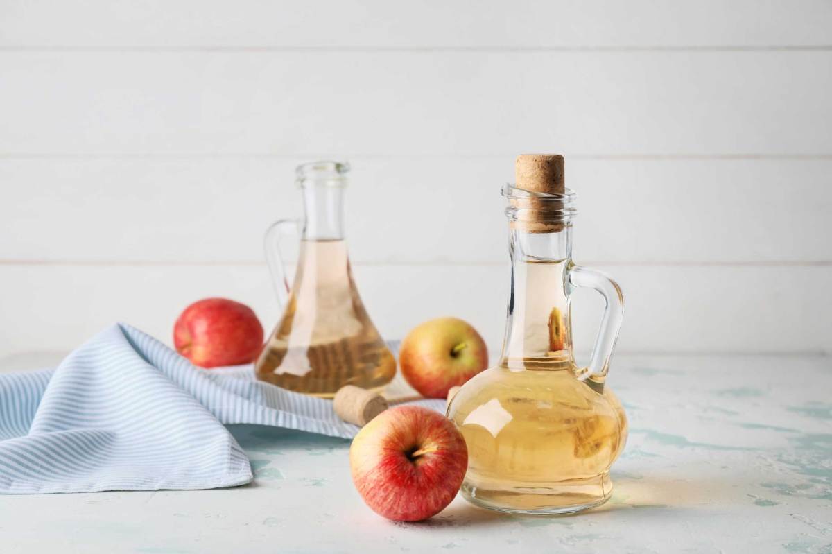 Flaschen mit Apfelessig auf weißem Tisch