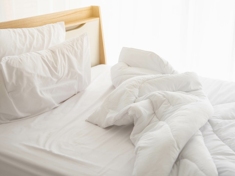 Ungemachtes Bett mit weißer Bettwäsche.
