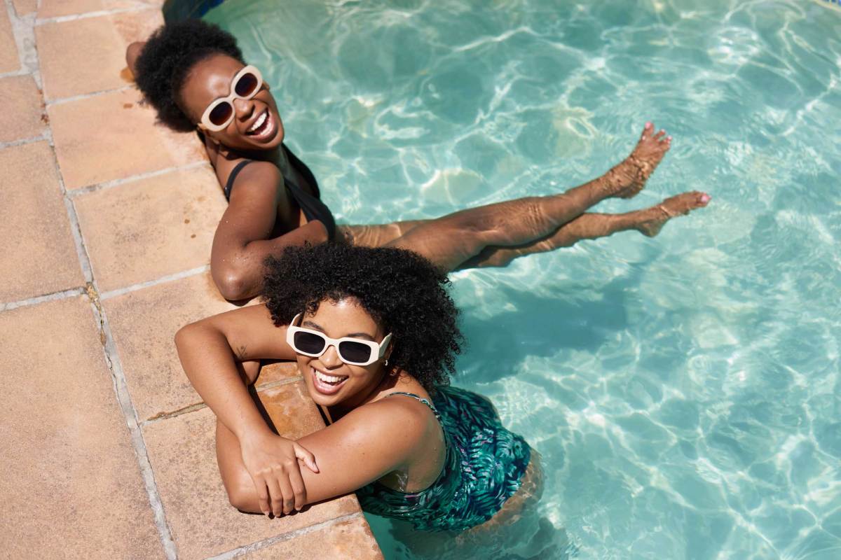 Zwei schöne Frauen kühlen sich im Schwimmbad ab, Hitzewelle im Sommer