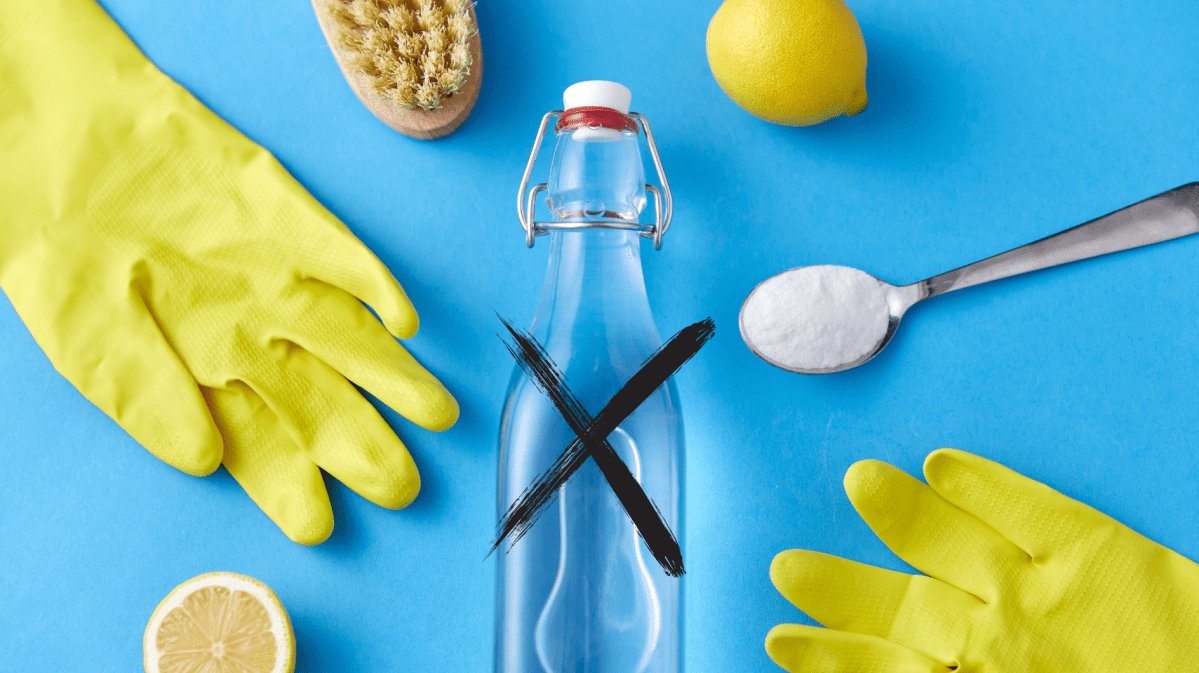 Handschuhe, Zitrone, eine Flasche Essig und Natron auf einem Löffel liegen vor einem blauen Hintergrund