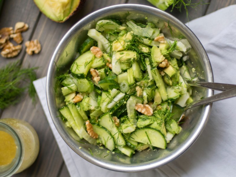 Gurkensalat mit Walnüssen und Dill in einer großen Metallschüssel.