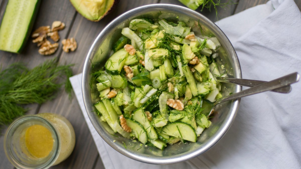 Gurkensalat mit Walnüssen und Dill in einer großen Metallschüssel.