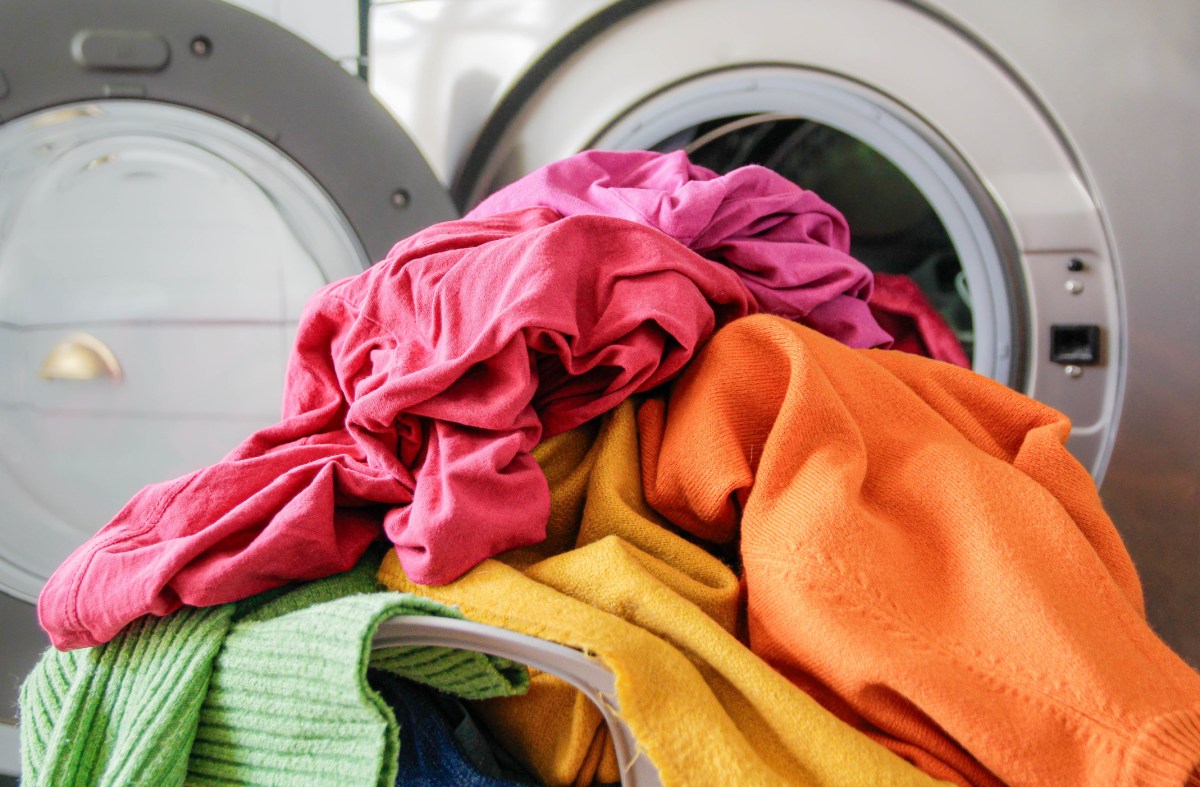 Waschmaschine mit buntem Kleiderhaufen davor
