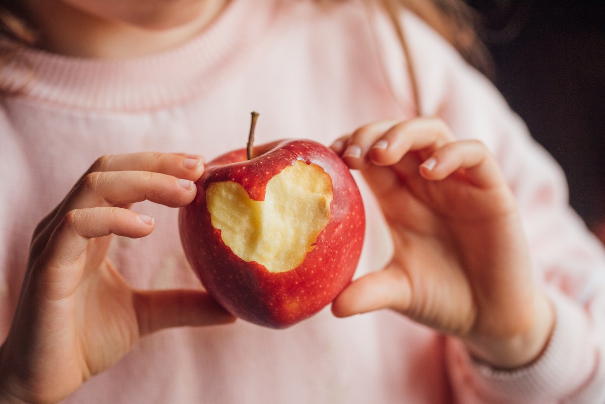 Hand mit Apfel, in dem Herz hineingebissen wurde