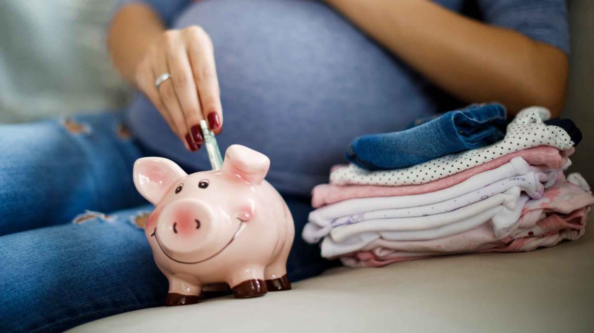 Schwangere Frau wirft Geldscheine in ein Sparschwein.
