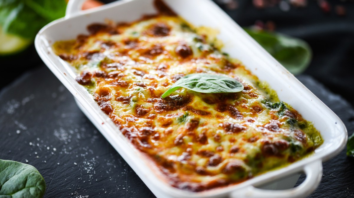 Lasagne mit Spinat in einer weißen Auflaufform.