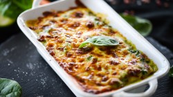 Lasagne mit Spinat in einer weißen Auflaufform.
