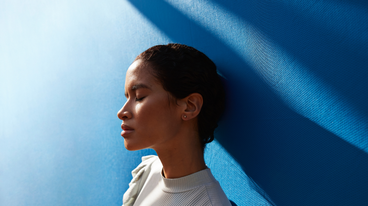 Frau vor einer blauen Wand blickt traurig