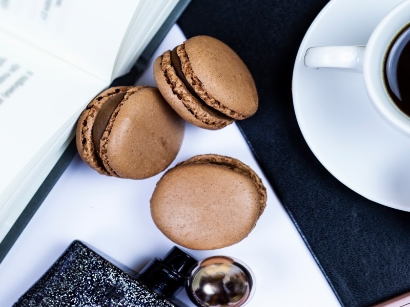 Tisch, auf dem eine Kaffee-Tasche und leckere Maccarons liegen.