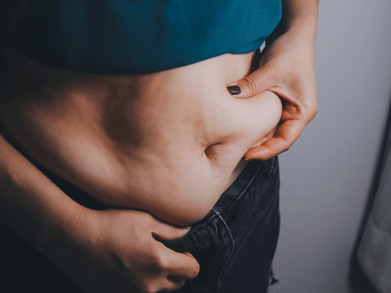 dicke Frau, dicker Bauch, mollig, fettleibige Frau Hand hält übermäßiges Bauchfett mit Maßband, Frau Diät Lebensstil Konzept