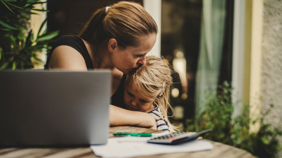 Mutter küsst ihre Tochter, ca. 4 Jahre, auf den Kopf, die traurig auf den Boden schaut.
