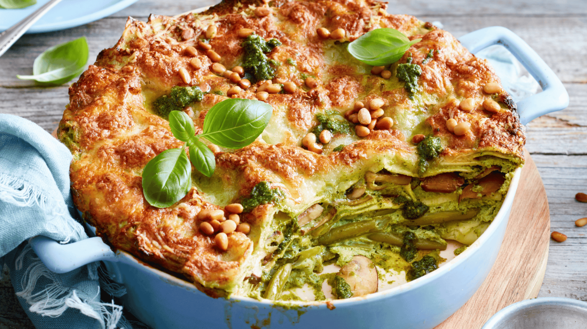 Pesto-Lasagne mit Pinienkernen in einer hellblauen Auflaufform.