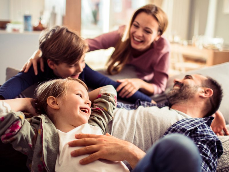 Glückliche vierköpfige Familie zusammen auf der Couch.