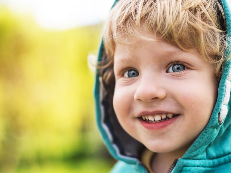 Nahaufnahme eines kleinen Jungen, vielleicht 3 Jahre alt, der seine Kapuze aufhat.