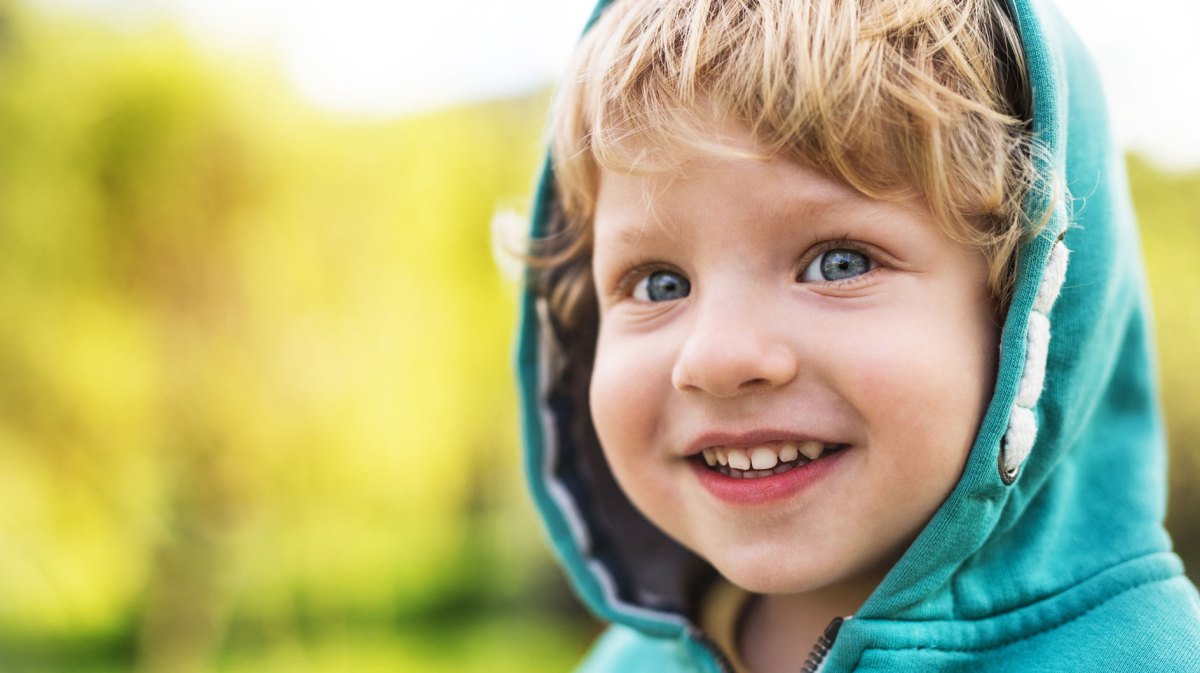 Nahaufnahme eines kleinen Jungen, vielleicht 3 Jahre alt, der seine Kapuze aufhat.