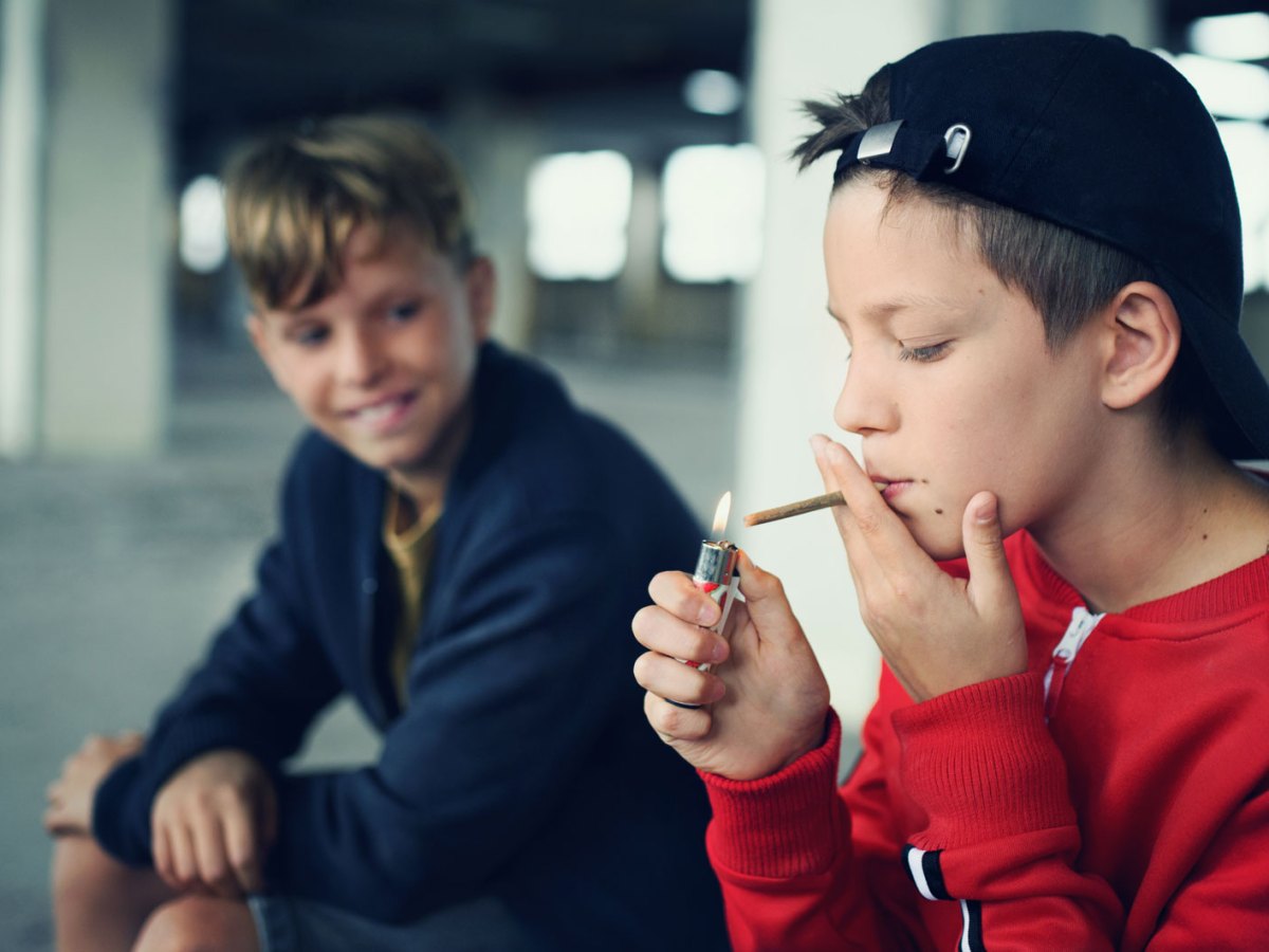 Jungs im Teenageralter, in einer Garage, rauchen heimlich.