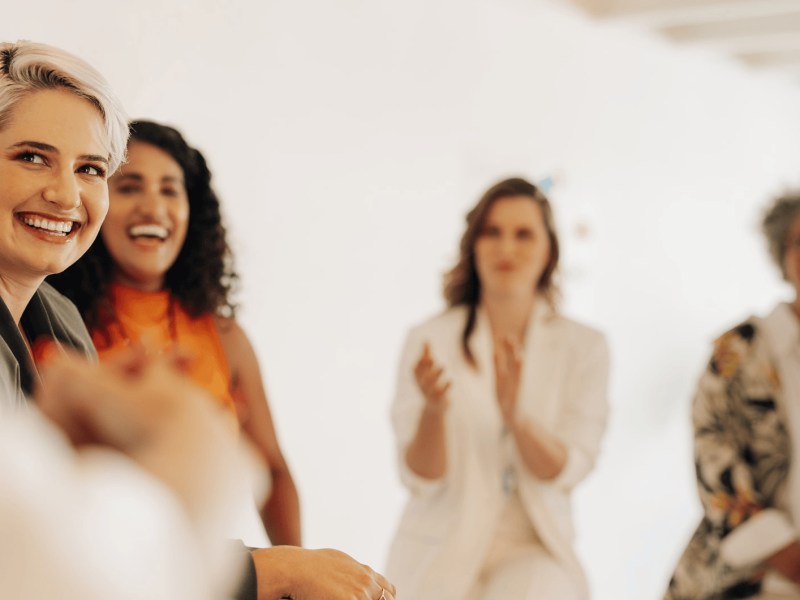 Mehrere Frauen sitzen zusammen und lachen.