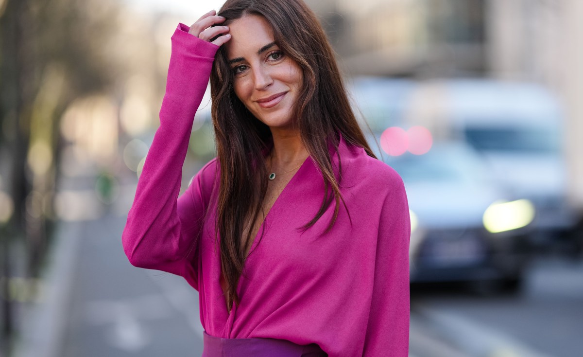 Brunette Frau mit pinker Bluse lächelt in die kamera, als Symbolbild für rosa Birkenstock Sandalen