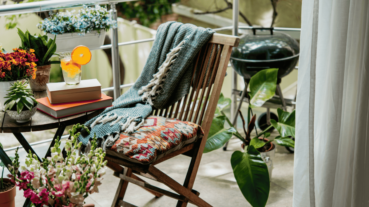 Pflanzen, Tisch und Stühle mit viel Deko auf einem kleinen Balkon