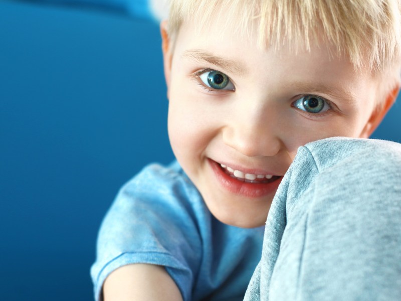 Porträt eines kleinen, glücklichen Jungen vor blauem Hintergrund.