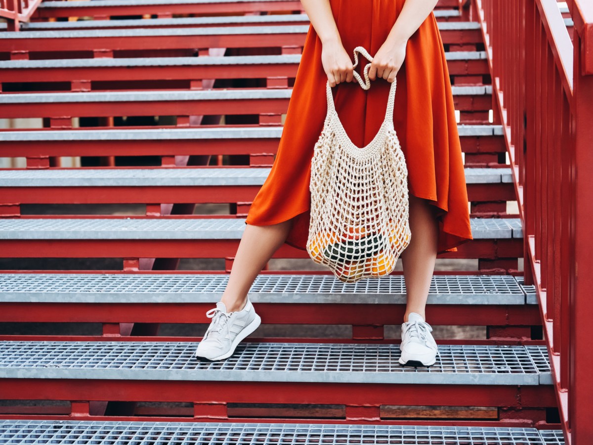 Frau mit weißen Sneakers und rotem Rock auf einer Treppe.