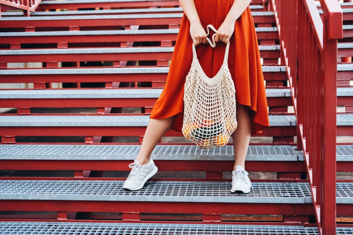 Frau mit weißen Sneakers und rotem Rock auf einer Treppe.