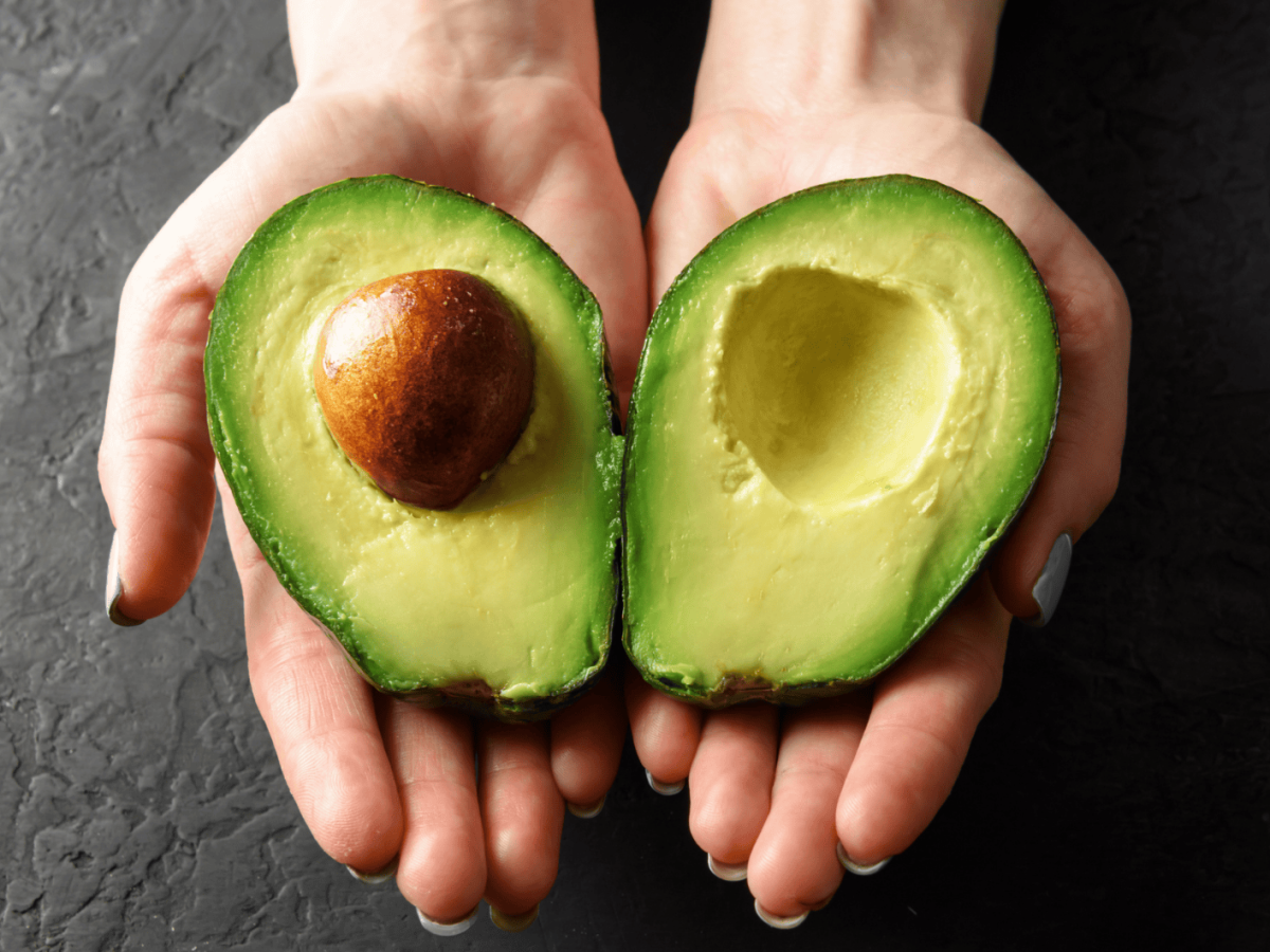 Frische Avocadofrucht in den Händen einer weiblichen Person. Das Konzept der gesunden Ernährung. Lebensmittel-Fotografie