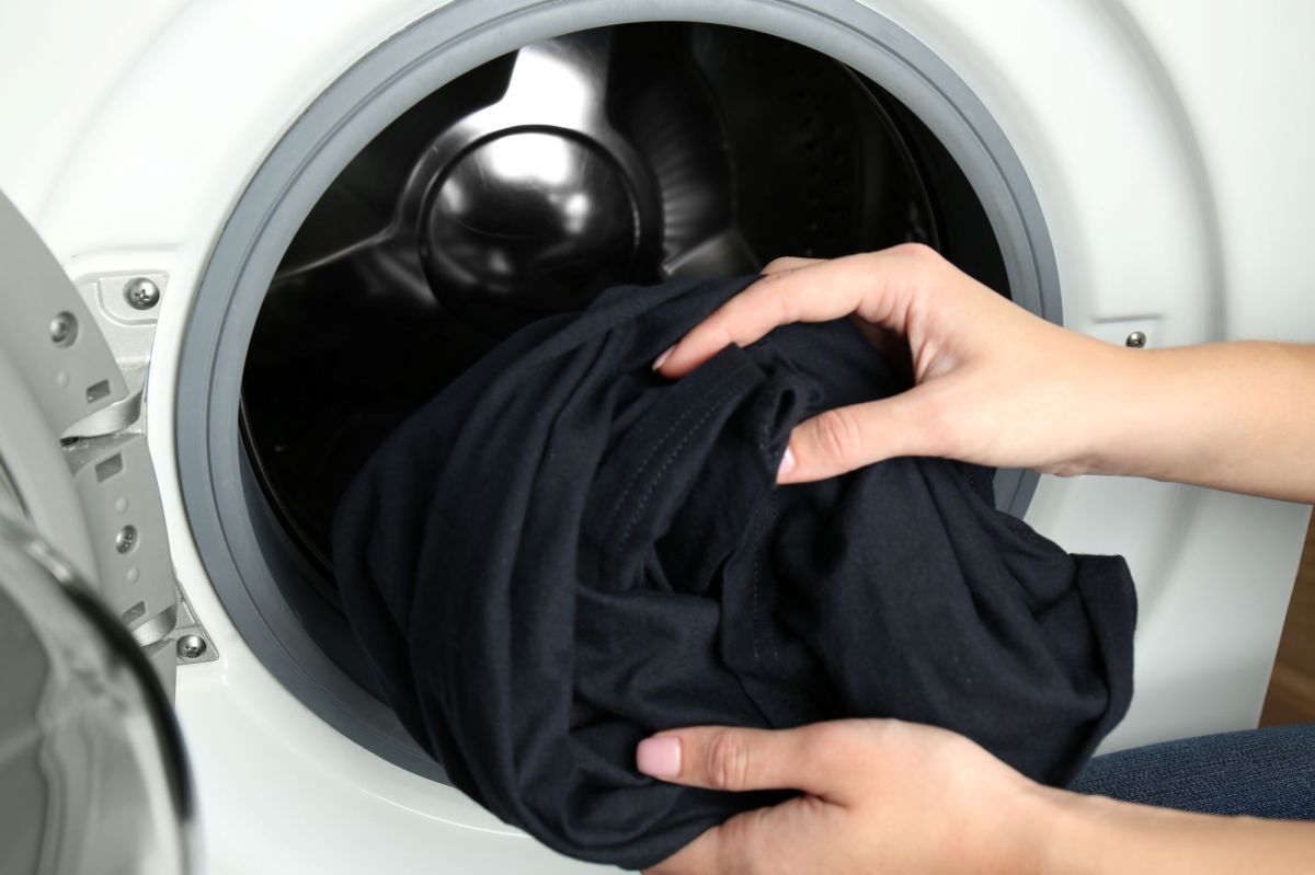 Hände nehmen schwarze Wäsche aus Waschmaschine