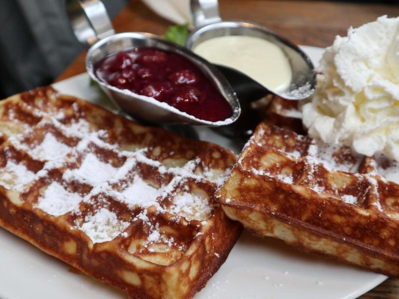 Belgische Waffeln mit Kirschen und Sahne und Puderzucker.