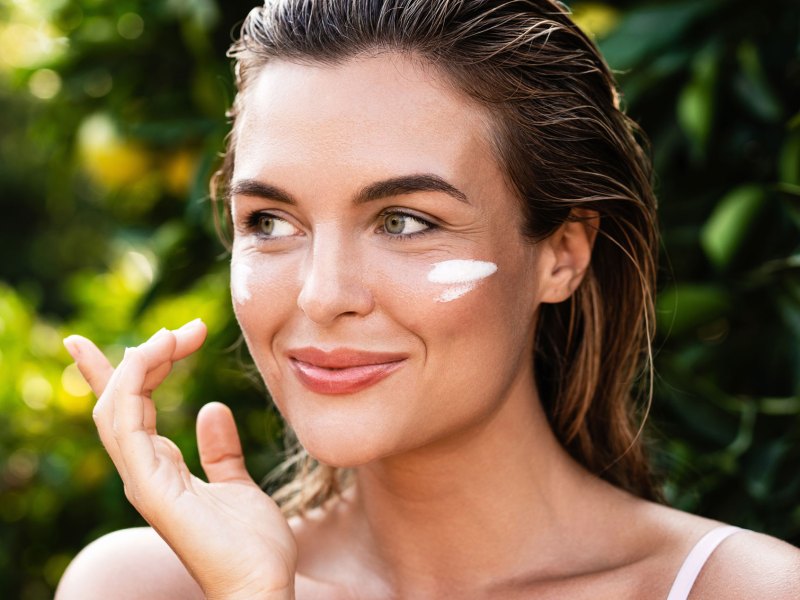 Frau mit Sonnencreme im Gesicht