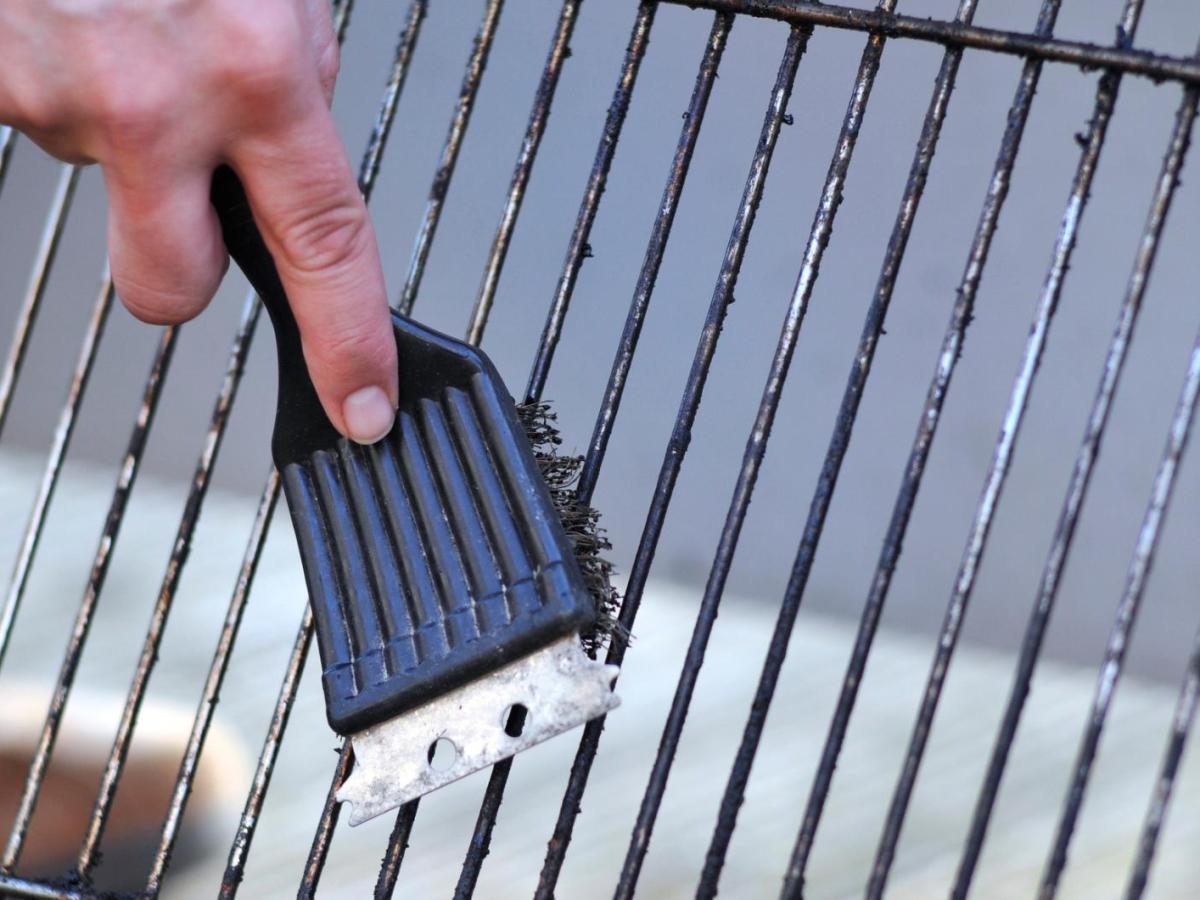 Grillrost wird mit einer Bürste gereinigt.