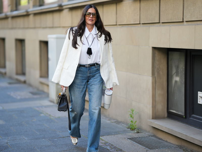 Frau mit trendigem Jeans-Outfit und weißer Bluse.