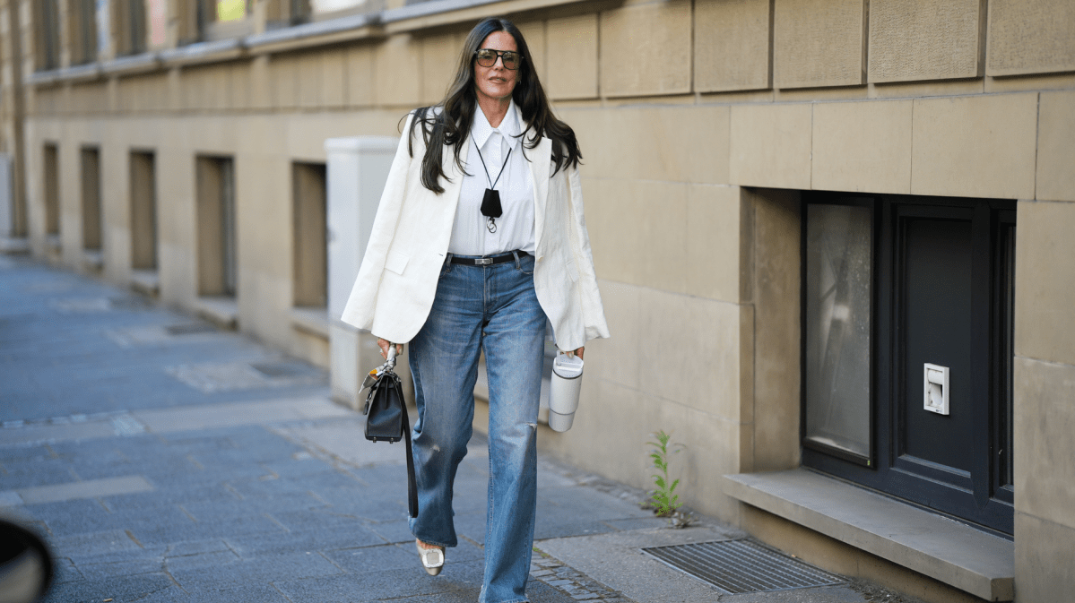 Frau mit trendigem Jeans-Outfit und weißer Bluse.