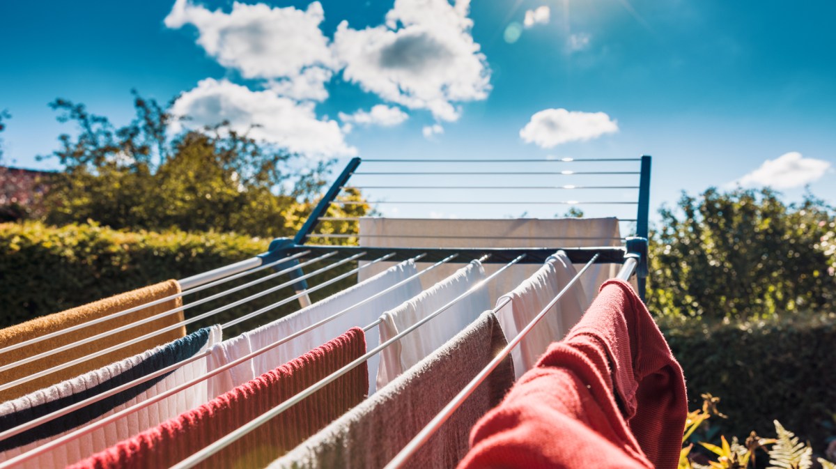 Bunte Kleidung hängt auf dem Wäscheständer und trocknet draußen in der Sonne.